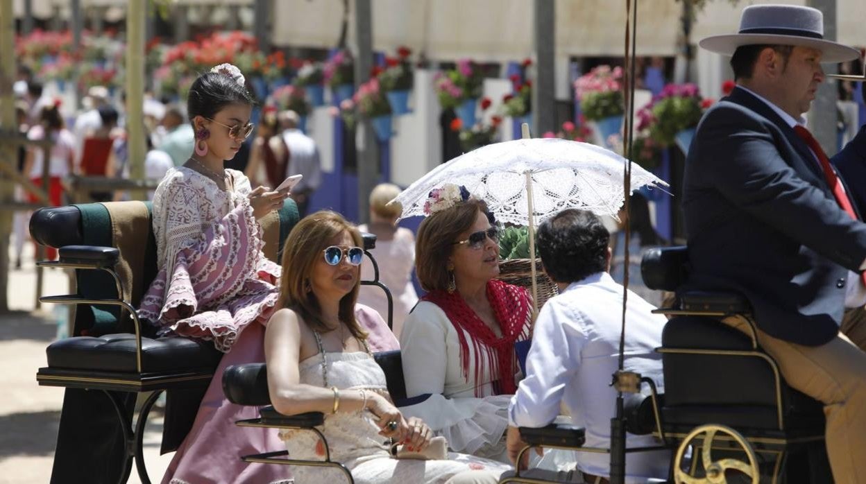 Una familia en coche de caballos con sombrilla y gafas de sol