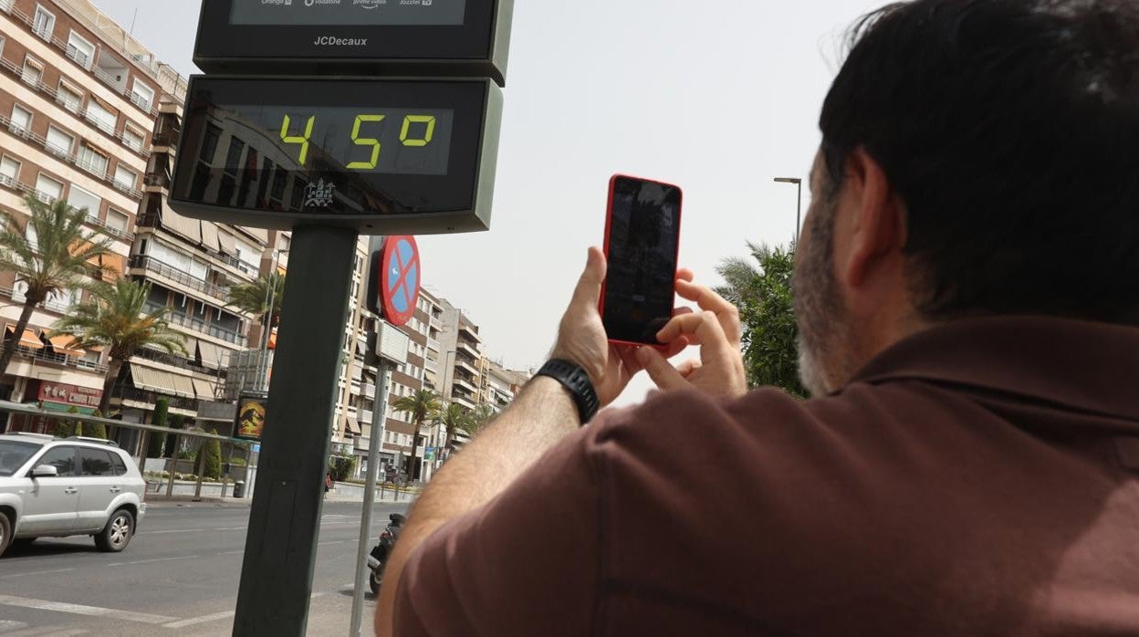 Un hombre fotografía un termómetro marcando 45 grados en el paseo de La Victoria