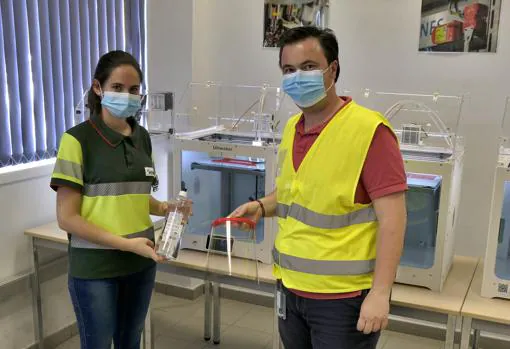 Dos empleados muestran la careta protectora y el gel desinfectante fabricado por la compañía