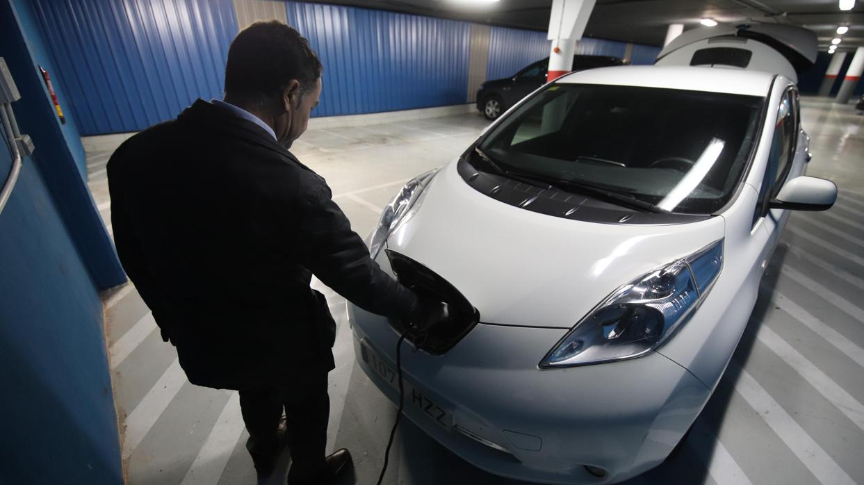 Un conductor enchufa su coche eléctrico en un punto de recarga