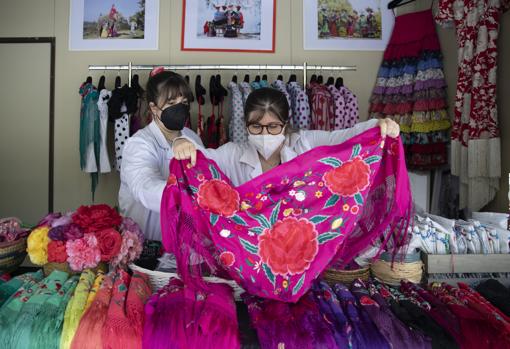 Dos mujeres desdoblan un mantoncillo en el mercadillo de moda flamenca de Sevilla. Las actividades económicas relacionadas con la Feria han sufrido un duro golpe, lo que hace temer por su supervivencia