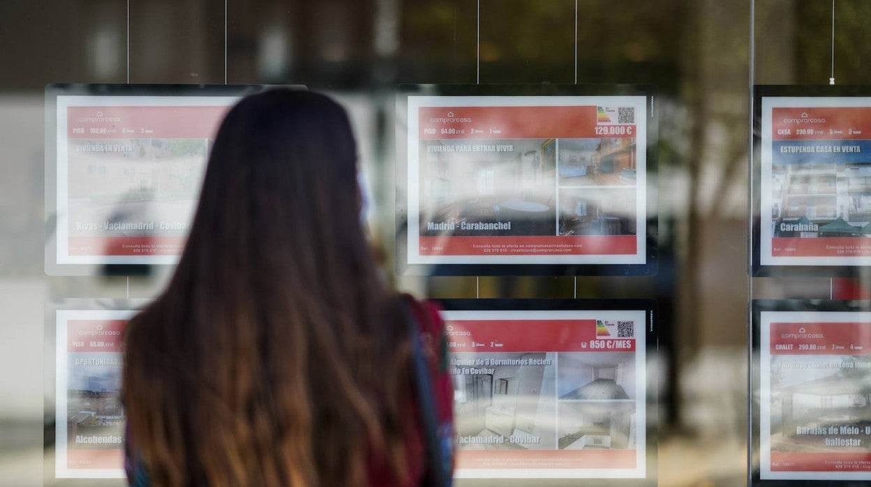 Una joven mira los anuncios de una agencia inmobiliaria