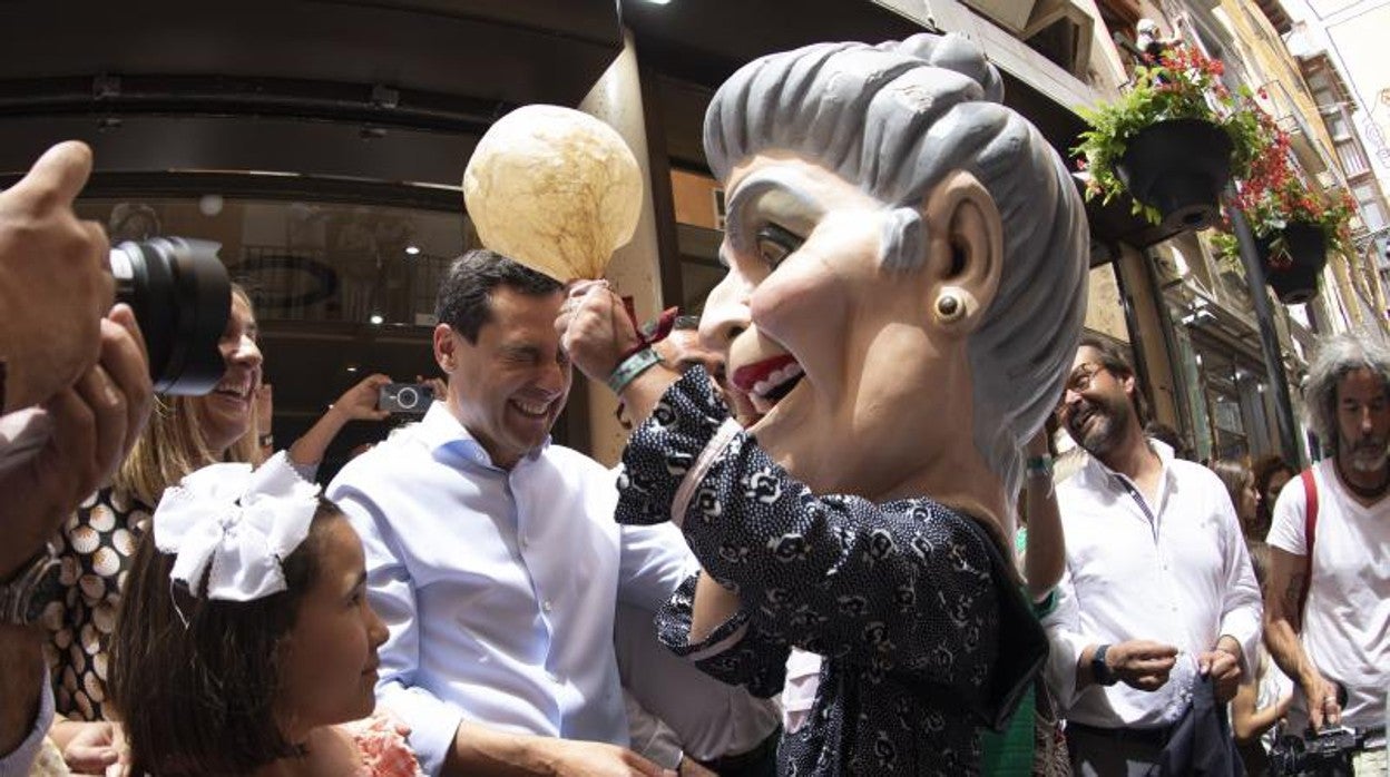 Juanma Moreno, ayer con uno de los tradicionales cabezudos en Granada