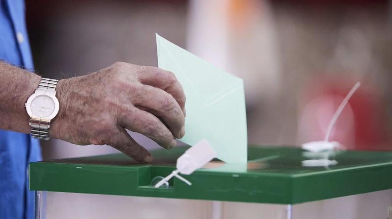 Un andaluz deposita su voto en una urna sevillana durante la jornada del 19-J