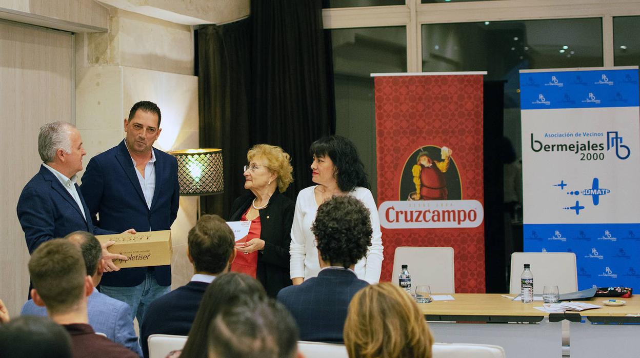 Álvaro Gotor (izquierda) y Conchita Rivas (tercera por la izquierda), vicepresidente y presidenta de la Asociación de Vecinos Bermejales 200, entregan el premio a los responsables de Filomena Tapas, Luis Ocaña e Inmaculada González