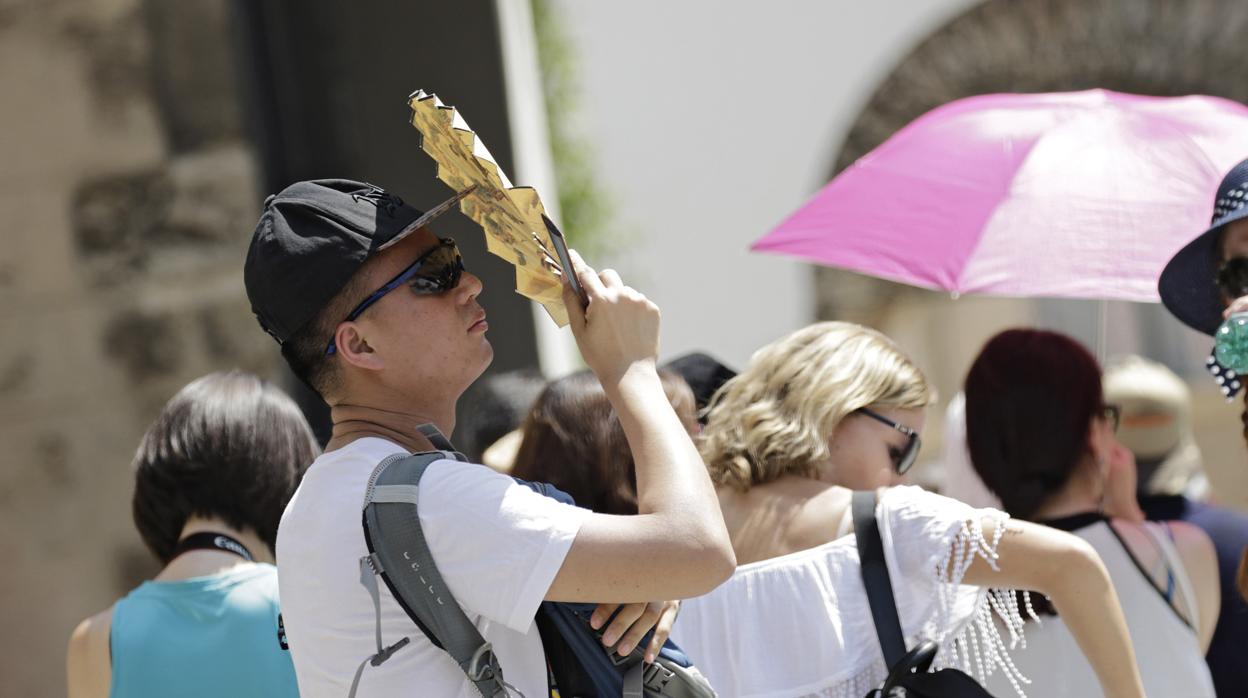 Un turista se protege del sol con un abanico en Sevilla