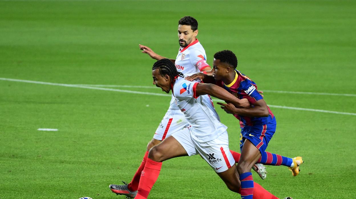 Koundé protege el balón ante la presión de Ansu Fati en presencia de Navas