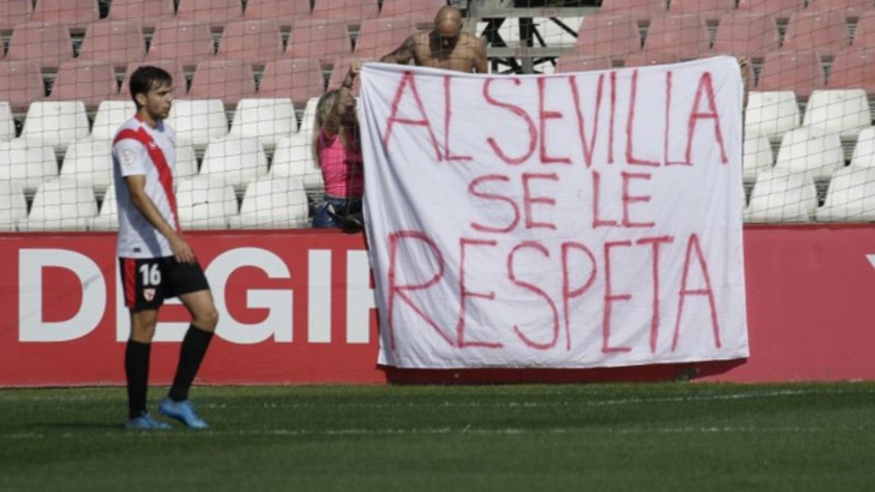 Juanmi García, penúltima baja del filial, juega un partido mientras dos aficionados colocan una pancarta