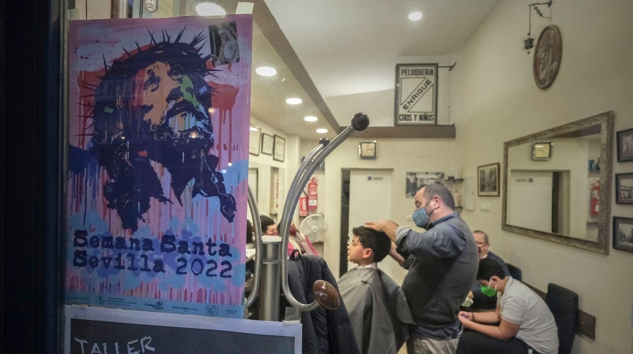 El barbero de la Alfalfa pela a un niño tras el cartel de la Semana Santa de Manolo Cuervo