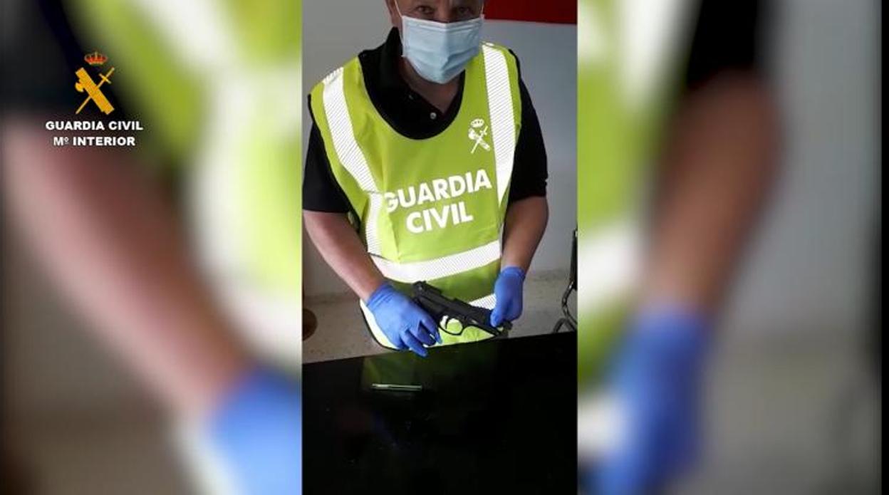 Un agente posa con la pistola intervenida al detenido en Castilblanco