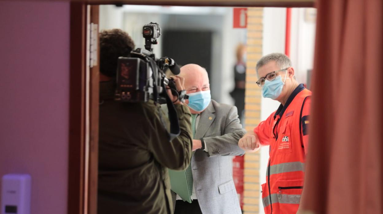 El consejero de Salud, Jesús Aguirre, saluda con el codo a un sanitario