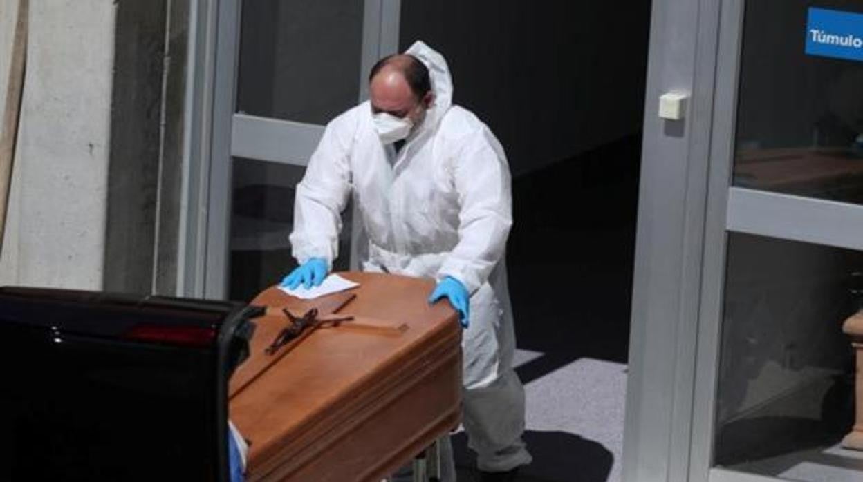 Un operario introduce un ataúd en un vehículo funerario