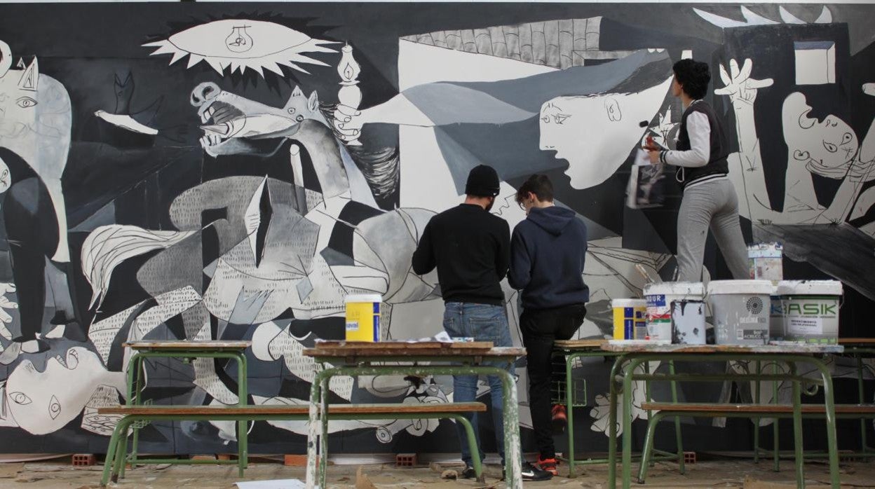 Tres alumnos perfilan una reproducción del cuadro del Guernica de Picasso