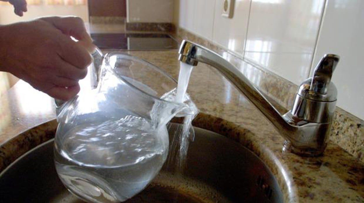 Una persona llena una jarra de agua de un grifo