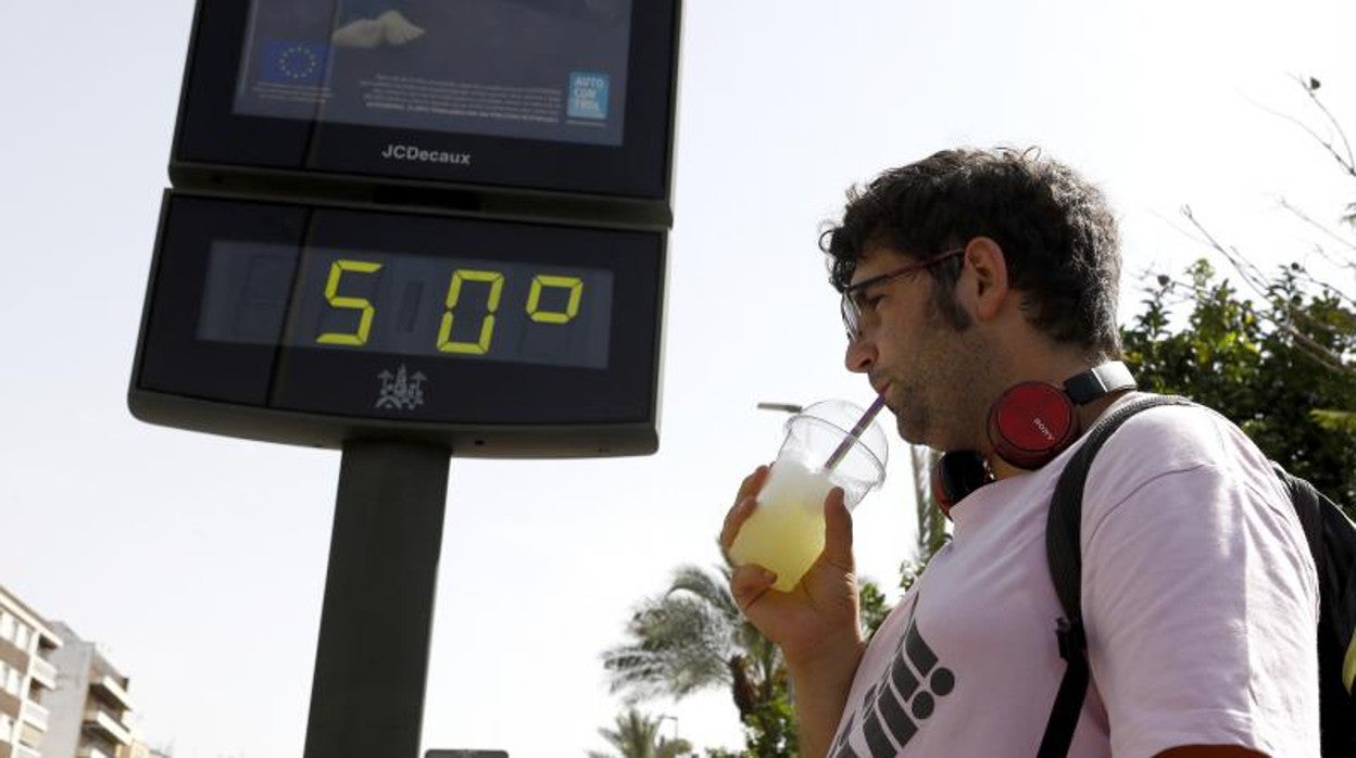 Un hombre se refresca con una limonada ante un termómetro que señala 50 grados
