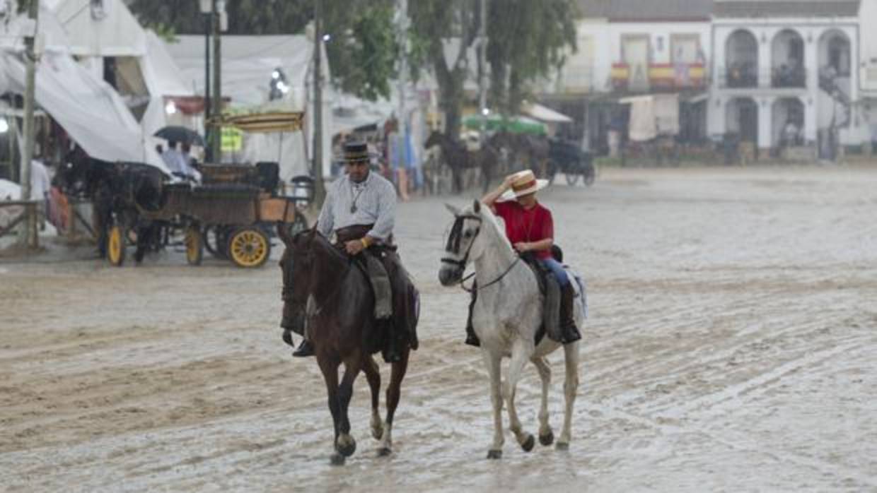 Caballistas sorprendidos por el aguacero que cae en la aldea del Rocío