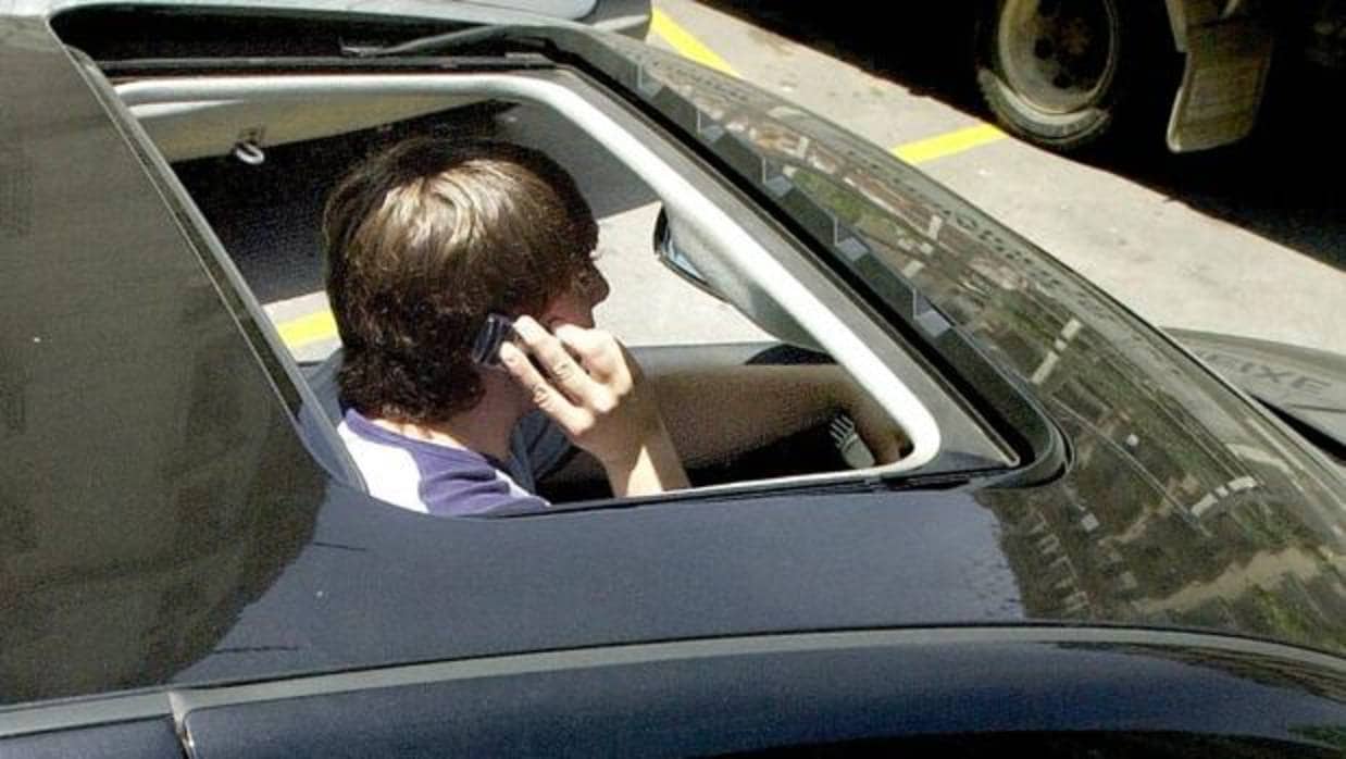 Un joven habla por el móvil en el interior de su vehículo