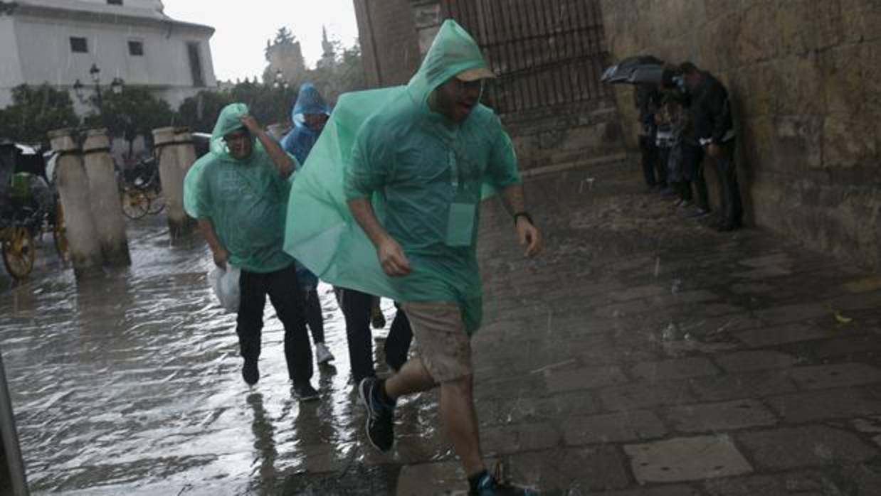 Un grupo de turistas corre a refugiarse de la lluvia