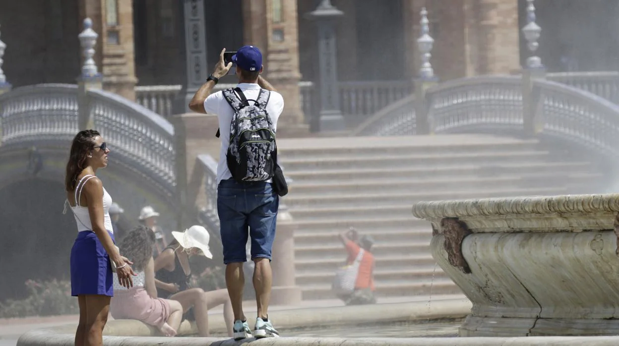 Turistas bajo un sol de justicia en la Plaza de España de Sevilla
