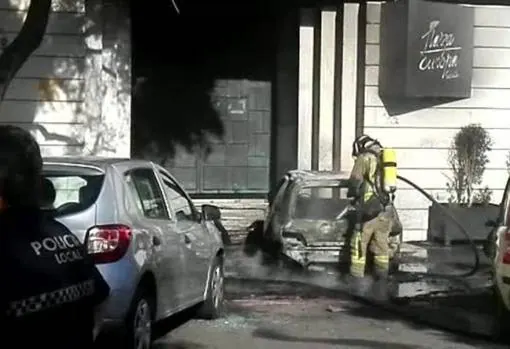 Un bombero refresca el vehículo que habían incendiado en la puerta de la discoteca