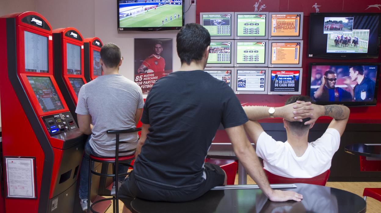 Varios jóvenes, ante las pantallas de apuestas deportivas de un salón de juegos