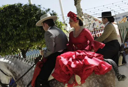 Un joven caballista junto a una mujer vestida de flamenca