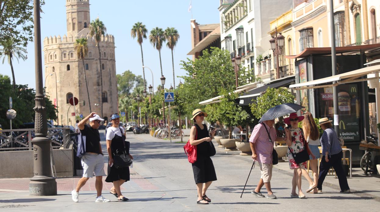 Turistas se protegen del sol durante su paseo por el centro de Sevilla