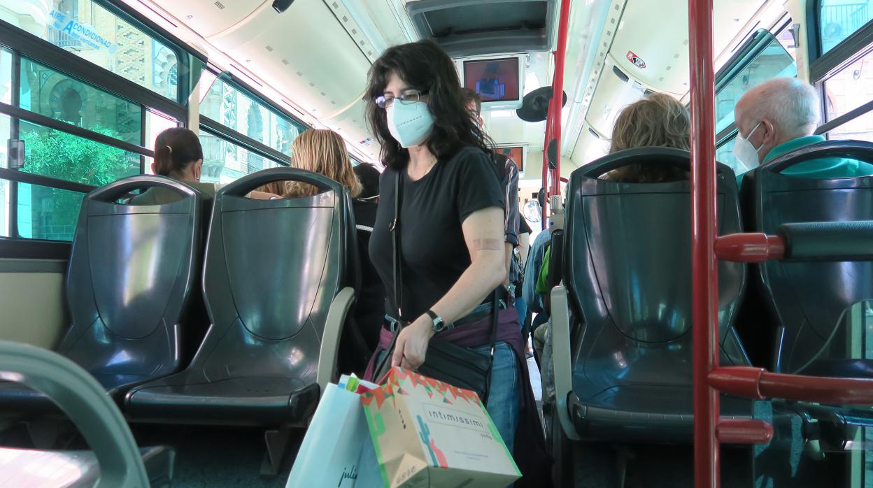 Una mujer accede a un autobús de Tussam con mascarilla tras ir de compras