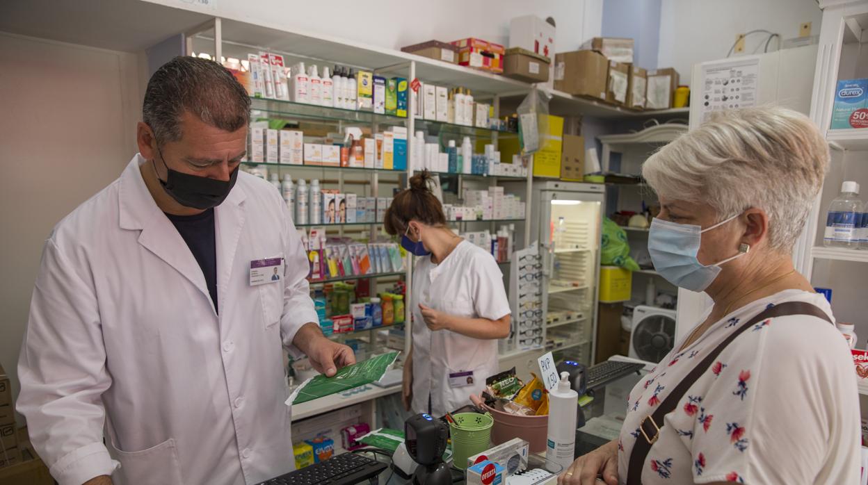 Una mujer compra un medicamento en una farmacia de Sevilla