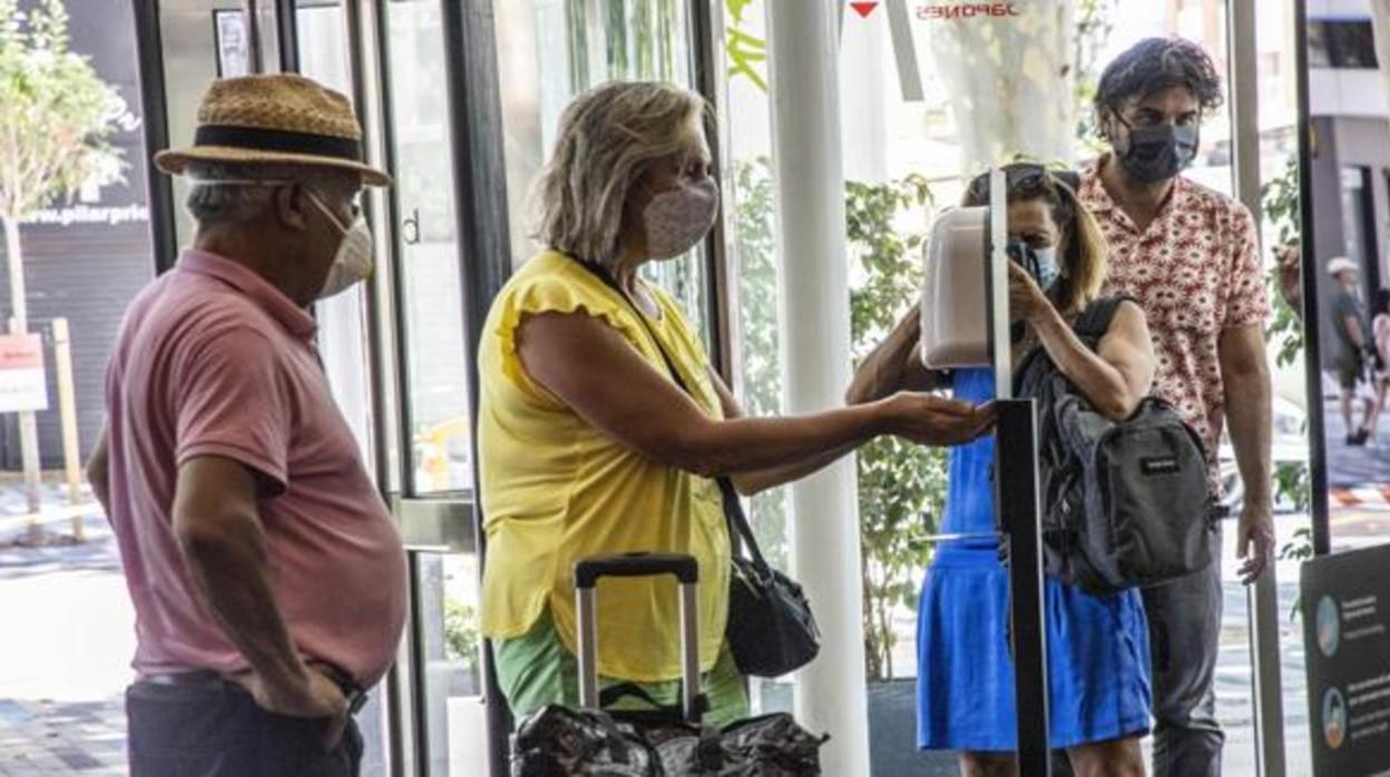 Varias personas aguardan para echarse hidrogel a la entrada de un establecimiento