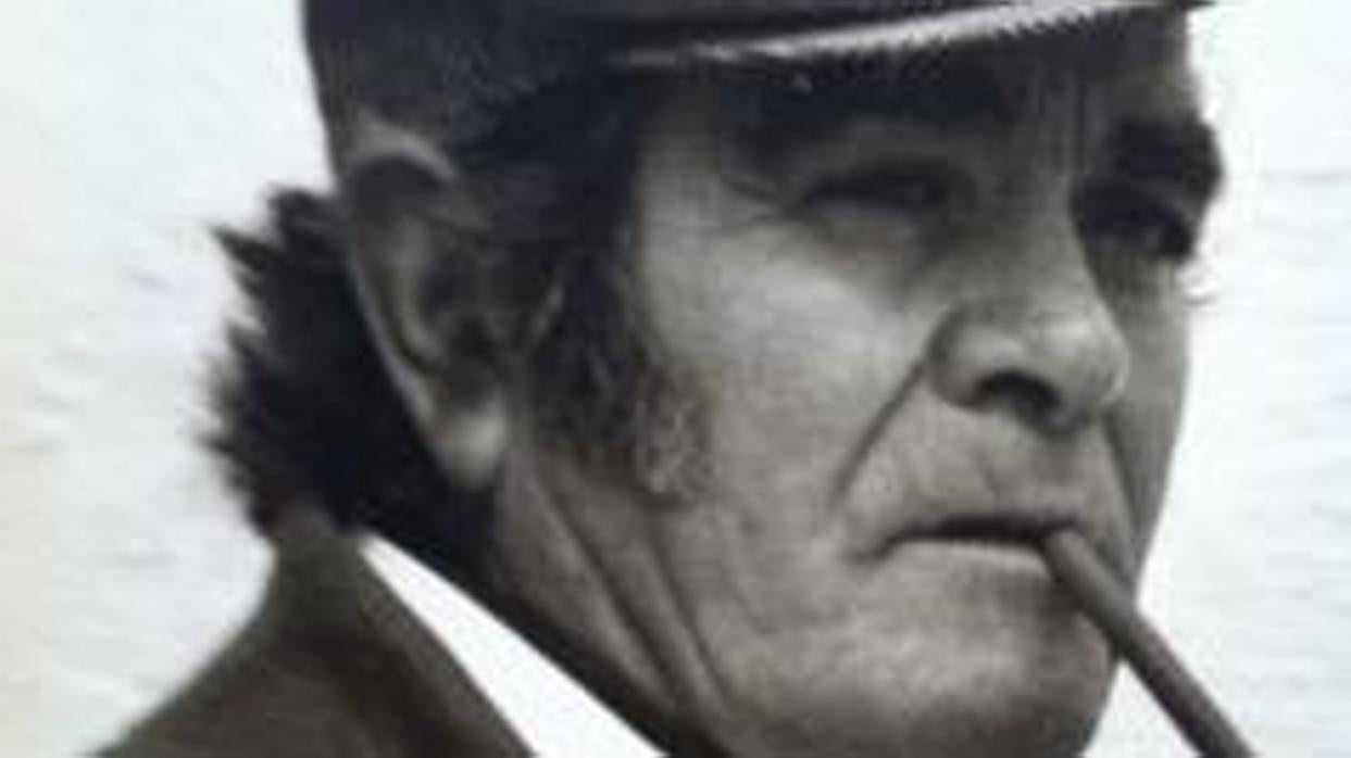 La imagen que mejor condensa la esencia de Isidro Muñoz Raposo. Gorrilla, traje oscuro, camisa blanca, pañuelo en la chaqueta