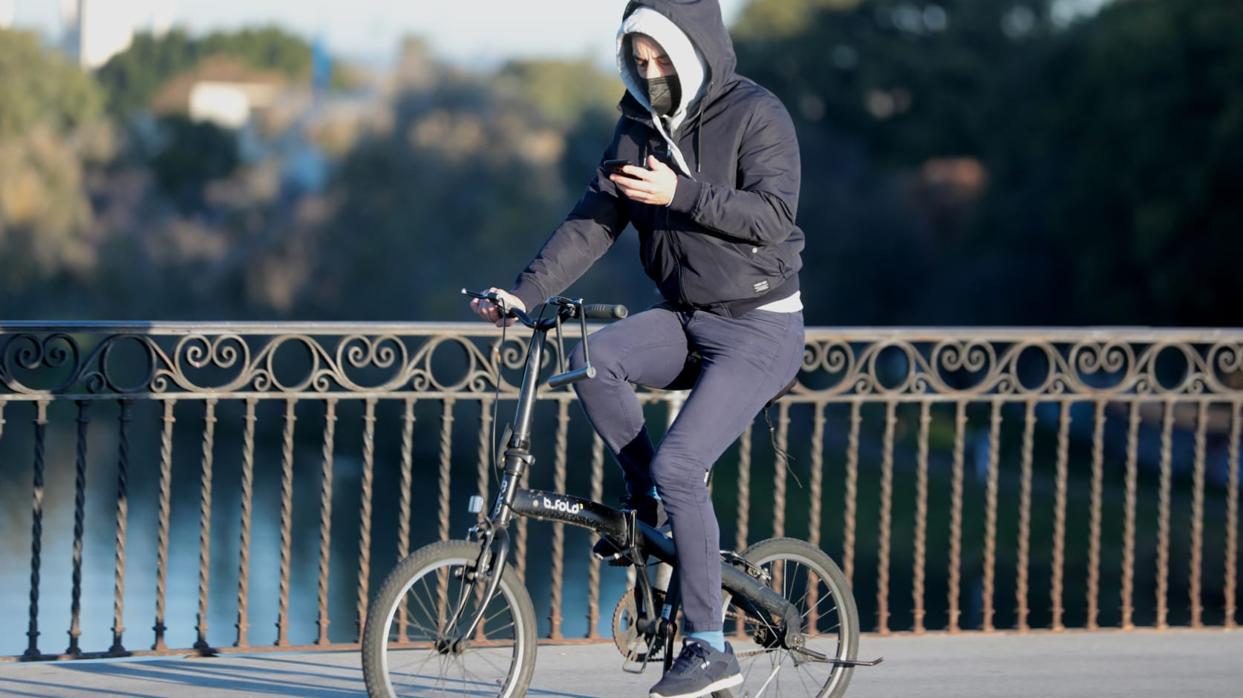 Un ciclista mira su teléfono móvil mientras pasea por Sevilla