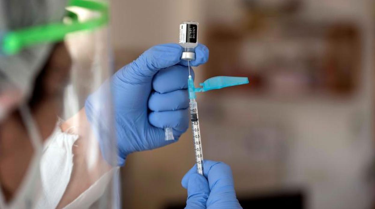 Un sanitario extrae el contenido de un bote de la vacuna contra el Covid