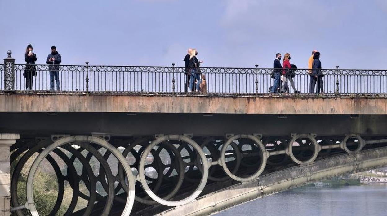 Varias personas pasean por el puente de Triana