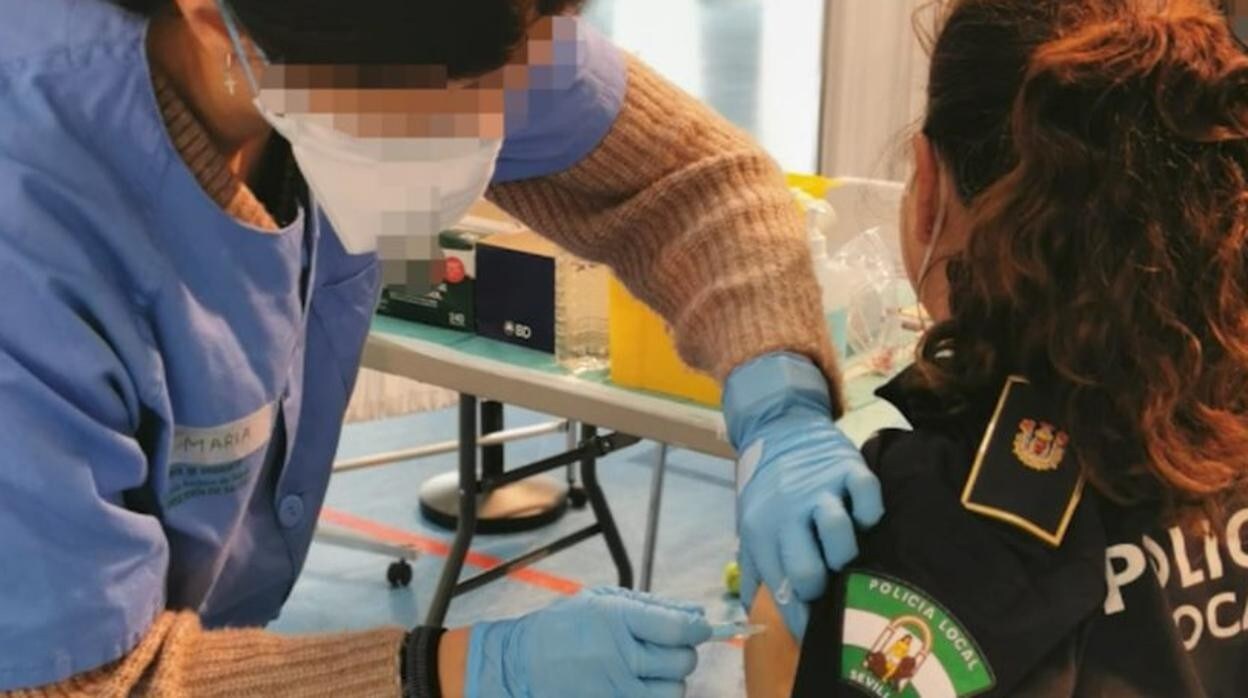 Una agente de la Policía Local de Sevilla recibe una dosis de la vacuna de AstraZeneca