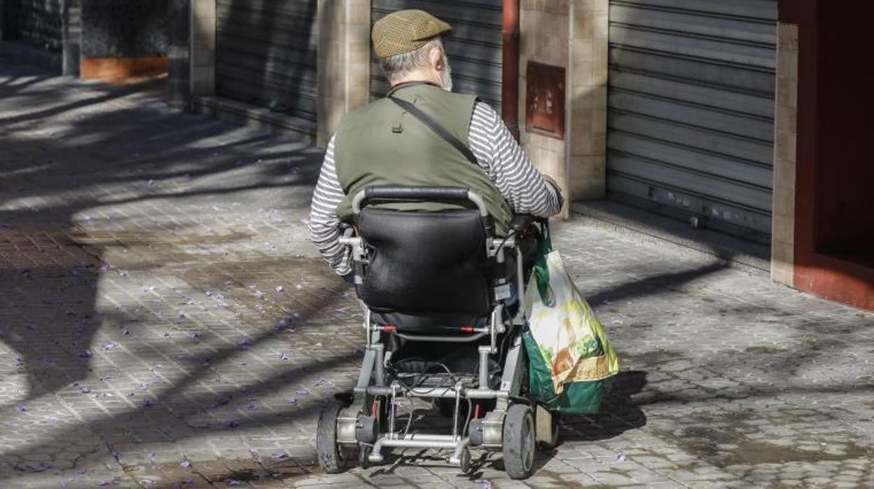 Una persona mayor en silla de ruedas transita por el barrio de Los Remedios