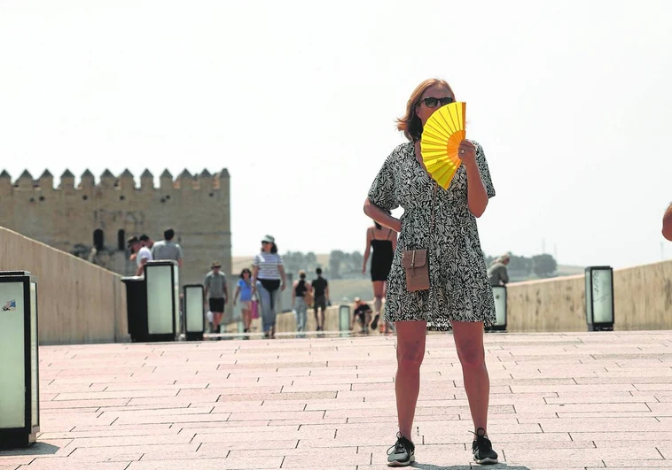 Una mujer desafía las elevadas temperaturas al sol en el Puente Romano de Córdoba