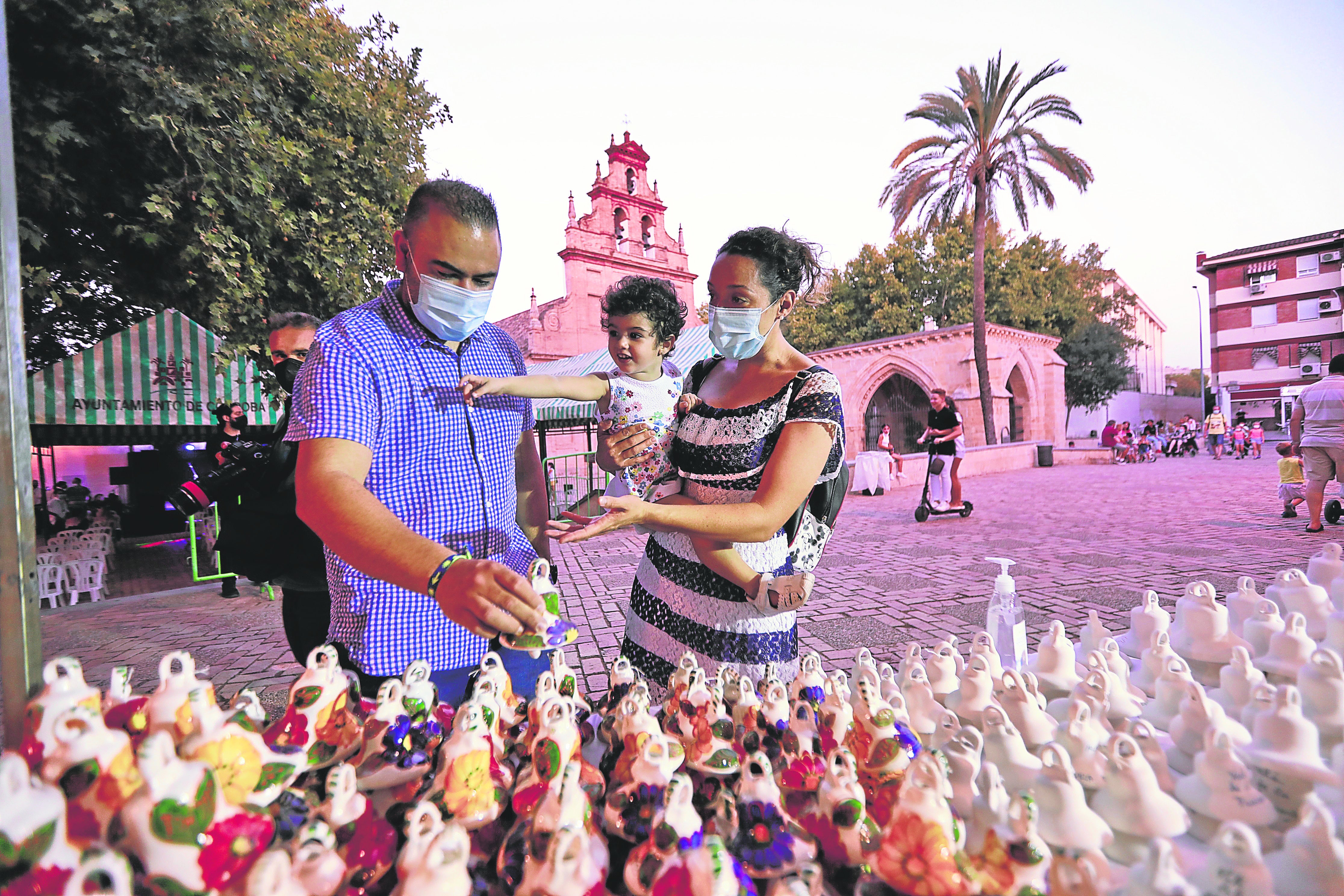 Una familia durante la Velá de 2021 visitando uno de los puestos de campanitas