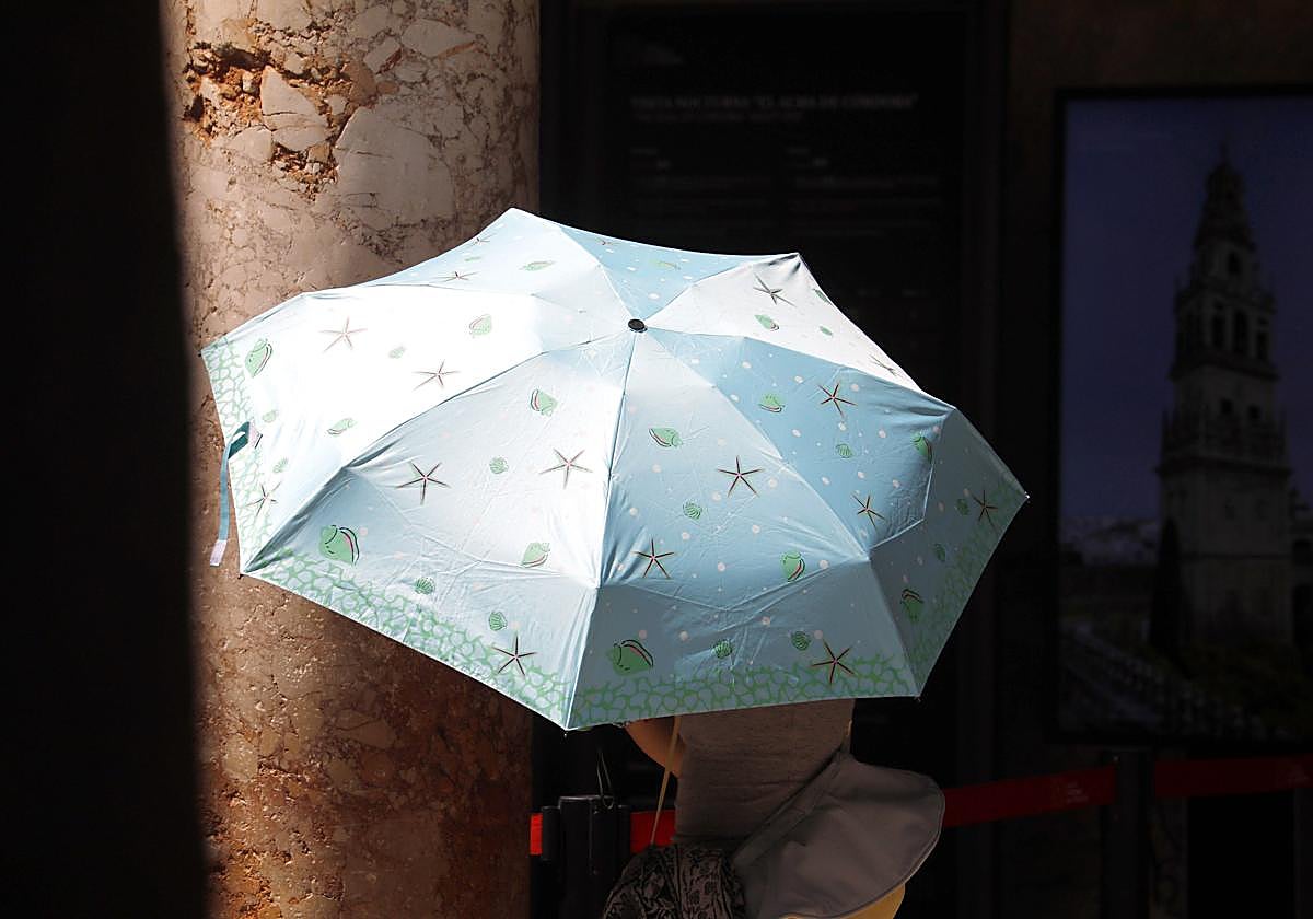 Una mujer se tapa del sol con una sombrilla durante su visita a la Mezquita-Catedral de Córdoba.