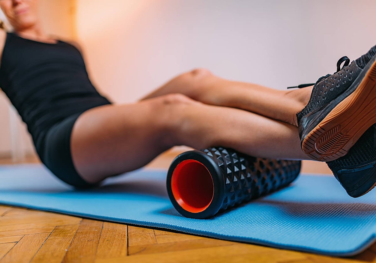 Una mujer, usando el 'foam roller'.