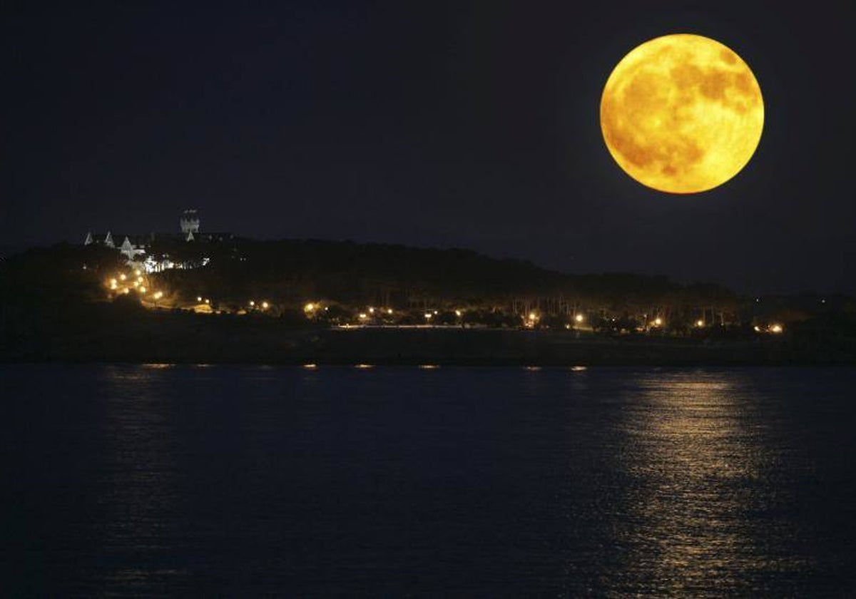 La luna, anaranjada, reflejada sobre el mar durante la noche