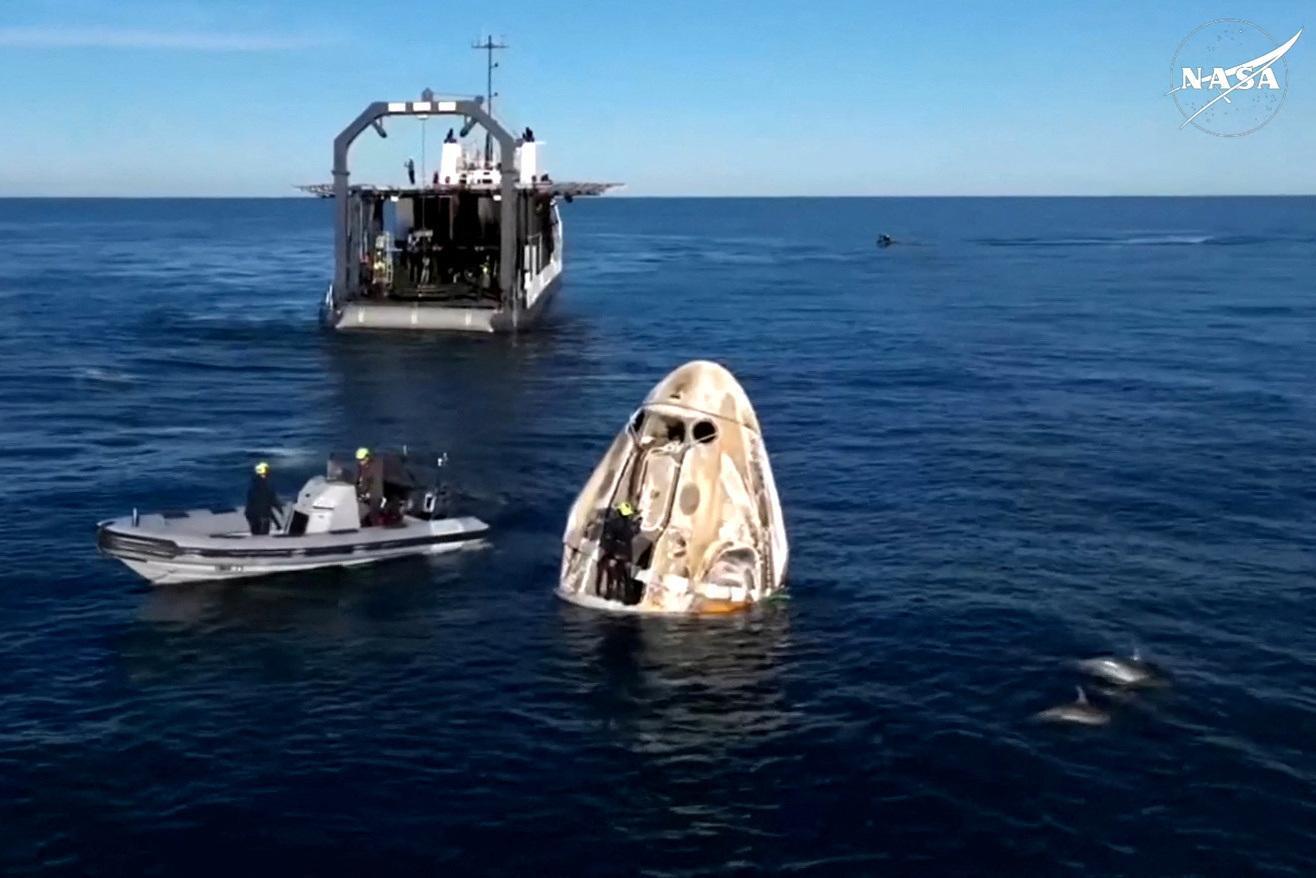 Atraídos por la operación, un grupo de delfines se aproxima para dar la bienvenida a los astronautas, junto al equipo de rescate