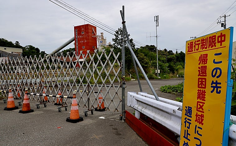 Imagen principal - «»«Acceso cerrado por ser zona de difícil regreso en el futuro, reza la señal ante la valla que impide el paso a una cementera próxima a la central nuclear de Fukushima 1 (primera imagen superior). En el puerto de Soma, a unos veinte kilómetros de la planta atómica, los pescadores temen el daño que provocará el vertido del agua tratada tras enfriar sus reactores fundidos (arriba a la izquierda). Visibles desde la Ruta 6, que pasa junto a la central, sacas negras y azules almacenan los escombros radiactivos de su desmantelamiento (arriba a la derecha). 