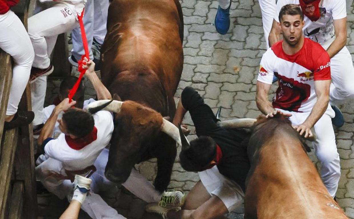 Dos toros de Cebada Gago embisten a varios mozo a su llegada al callejón durante el quinto encierro.