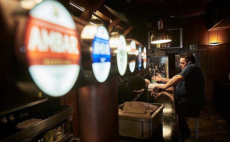 Imagen principal - Santos Muñoz tomando nota de reservas en el bar y ante la barra de la plaza del Castillo. Detalle de uno de sus almacenes