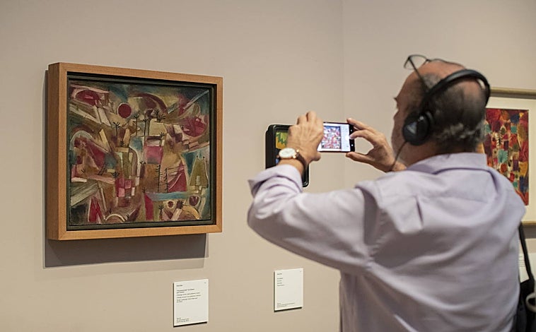 Imagen principal - La exposición recorre toda la producción de Klee, desde sus primeros estudios botánicos a las pinturas que realizó con los dedos en sus últimos días, y reúne más de 200 piezas entre dibujos, pinturas, documentos y objetos variados. Sobre estas líneas, un visitante fotografía una de los óleos de la exposición. Debajo, 'Viene el invierno', de 1939, una de sus últimas obras; y un estudio botánico de 1892. 