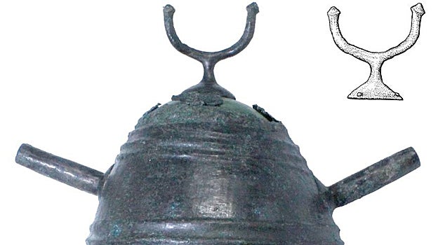 Fotografía frontal de uno de los cascos, con dibujo de la cimera con cuernos embolados