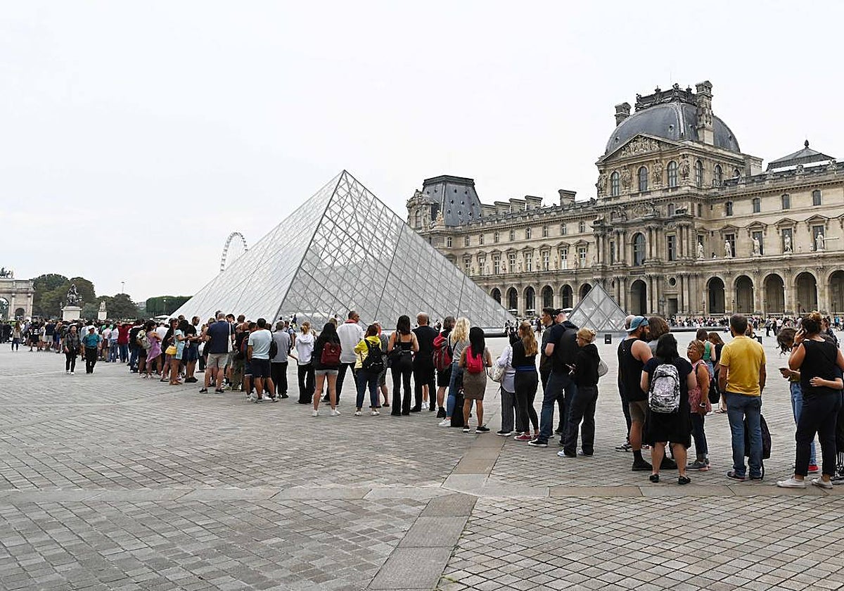 Los visitantes hacen cola frente a la Pirámide del Louvre