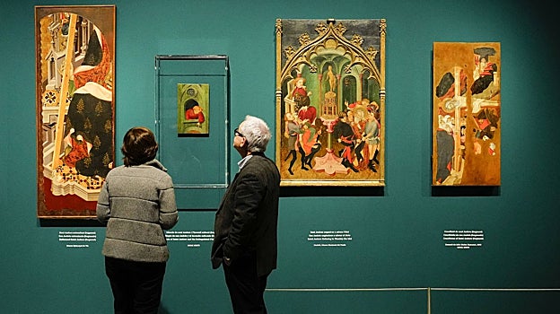 Dos visitantes observan piezas del retablo de san Andrés