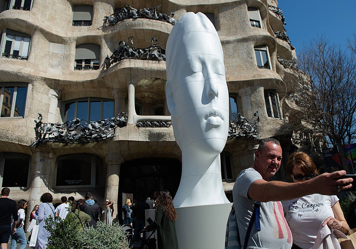 Una pareja se fotografía frente a al escultura de Plensa que recibe al visitante en la Pedrera